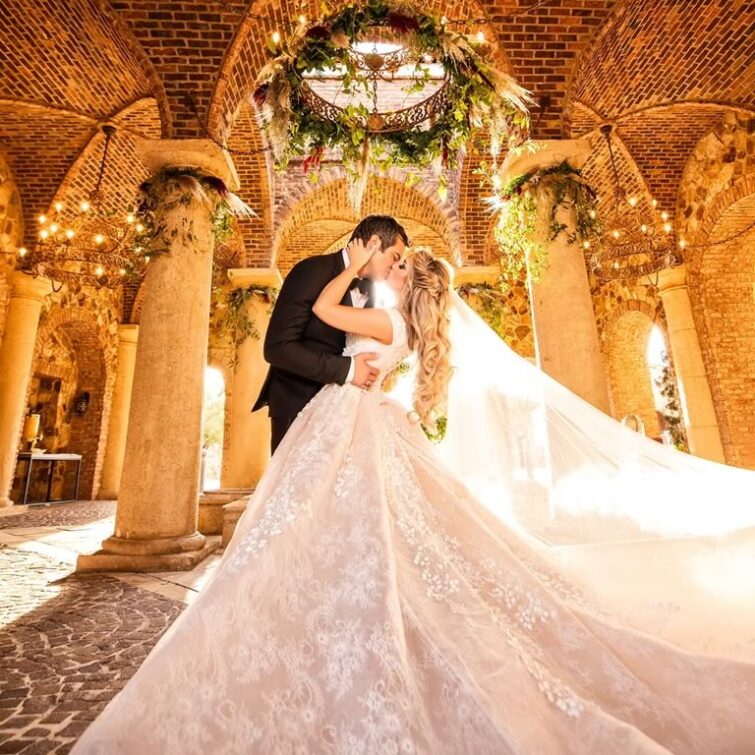 Romantic Couple Kissing in Well-Lit Chapel after Bride's Hair and Makeup by KADT