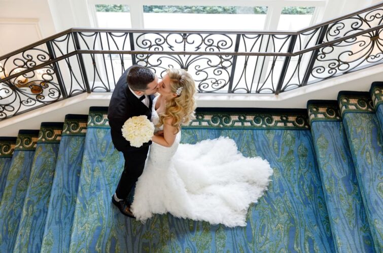 Bride and Groom Kissing on Blue Staircase with Stunning Hair and Makeup by Kristy's Artistry Design Team