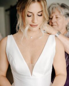 Heartwarming moment: Mom delicately puts on the bride's necklace, who looks stunning with hair and makeup by Kristy's Artistry Design Team in Orlando, FL.