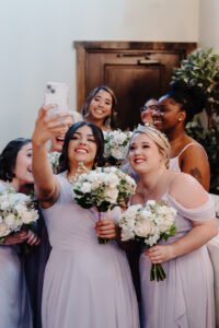 Fun selfie moment: Bride captures joy with her bridesmaids, all flaunting gorgeous hair and makeup by Kristy's Artistry Design Team.