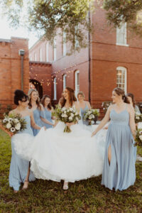 Smiling Bride with Six Bridesmaids Holding Flowers, Hair and Makeup by Kristy's Artistry Design Team