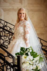 Smiling Bride on Staircase Holding Bouquet with Perfect Hair and Makeup