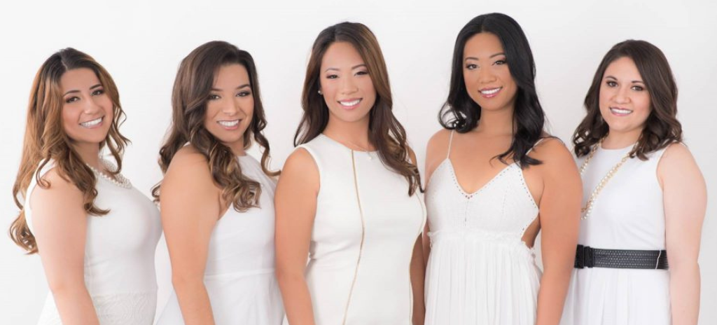 Bride and 4 bridesmaids smiling in white dresses after hair and makeup by Kristy's Artistry Design Team