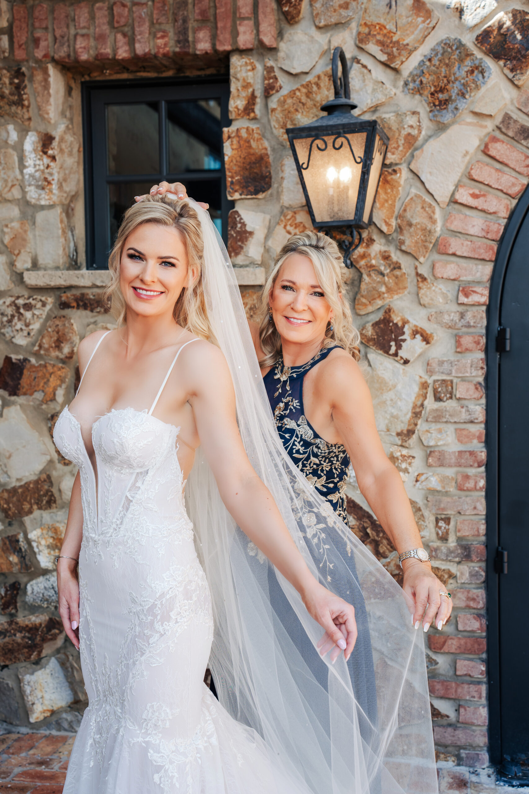 Mother of the bride and bride posing in front of the venue with hair and makeup done by Kristys Artistry Design Team.