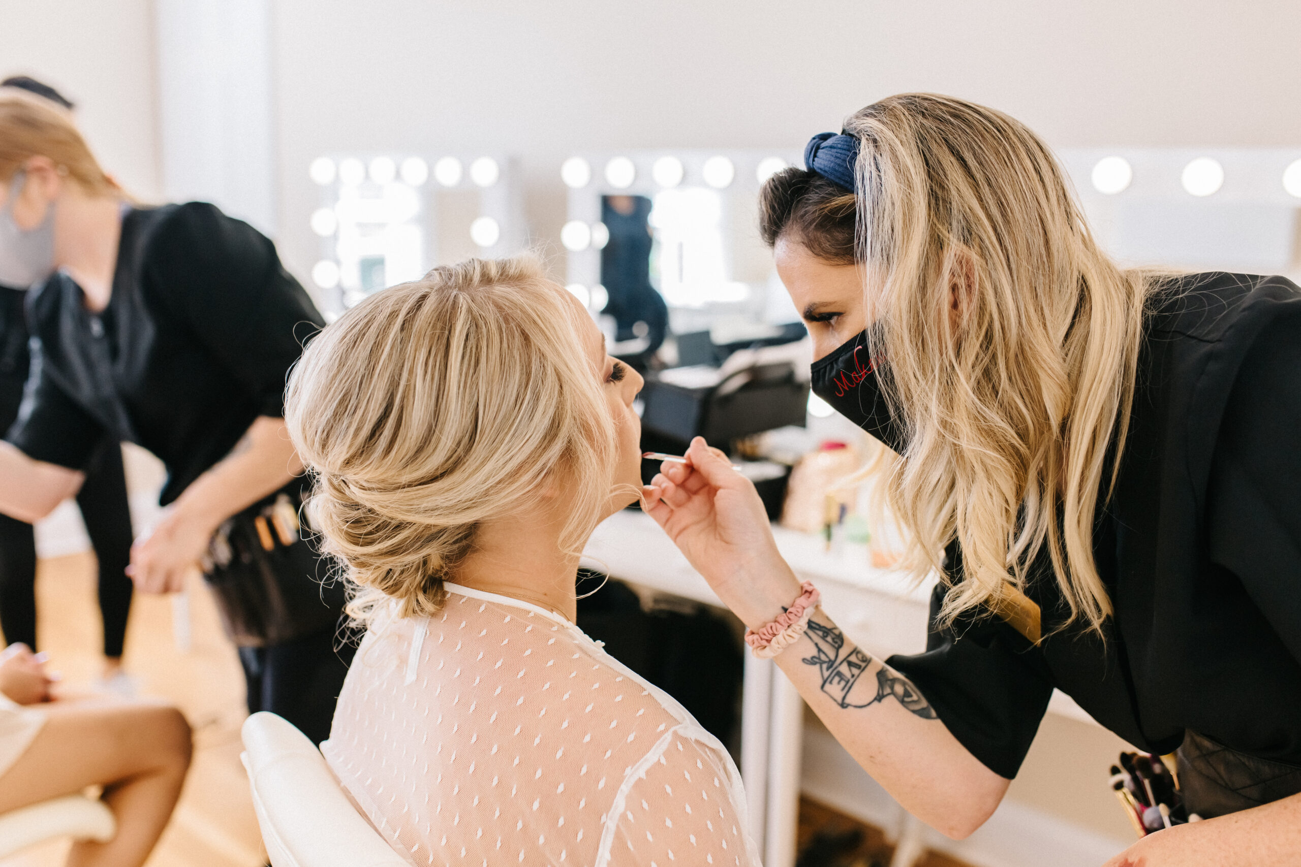 Artist from Kristy's Artistry Design Team applying lip gloss to a bride in the bridal suite pre-wedding.