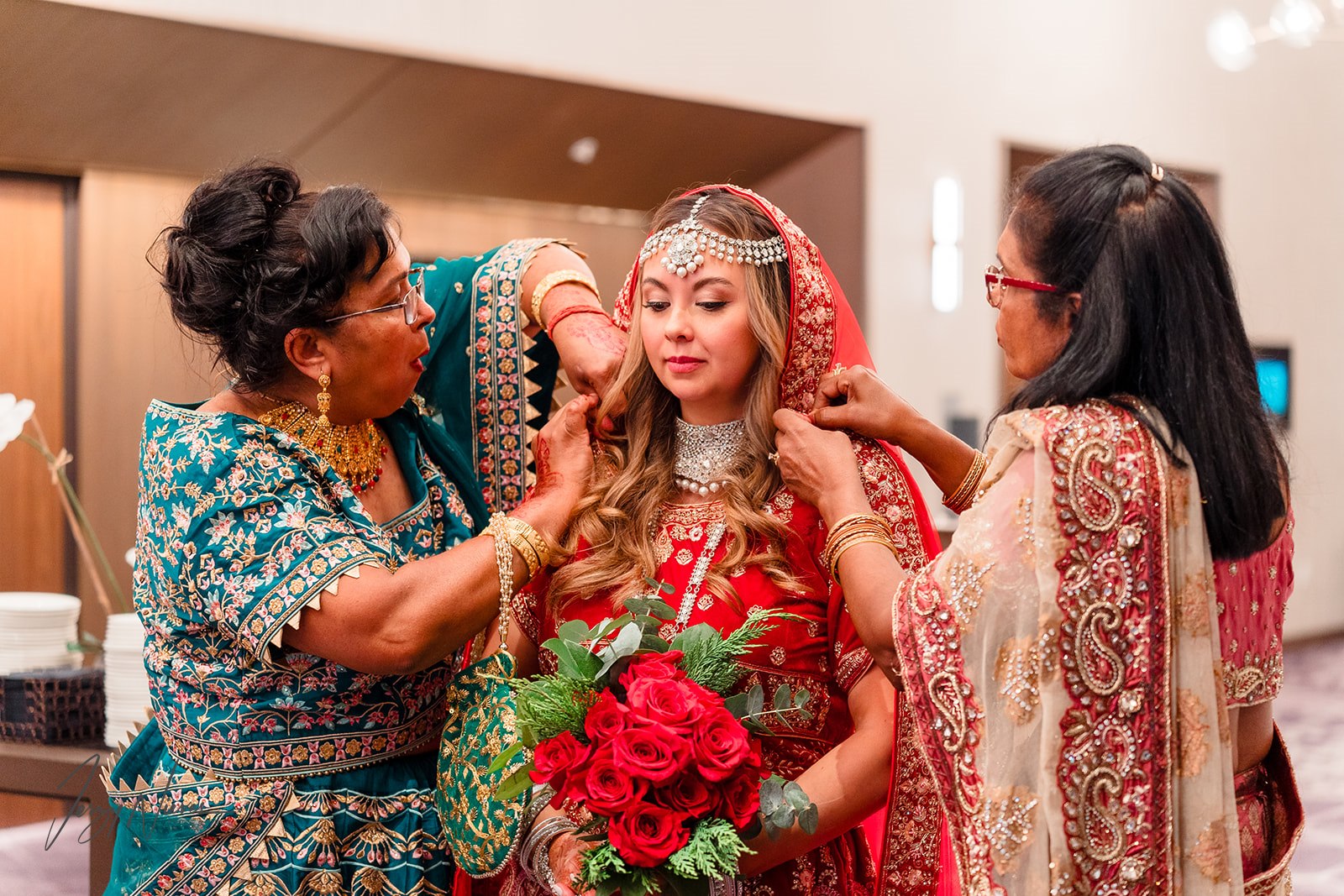 Traditional Indian wedding bride at Disney Swan Reserve receiving finishing touches to her dress, with wedding hair and makeup done by Kristy's Artistry Design Team.