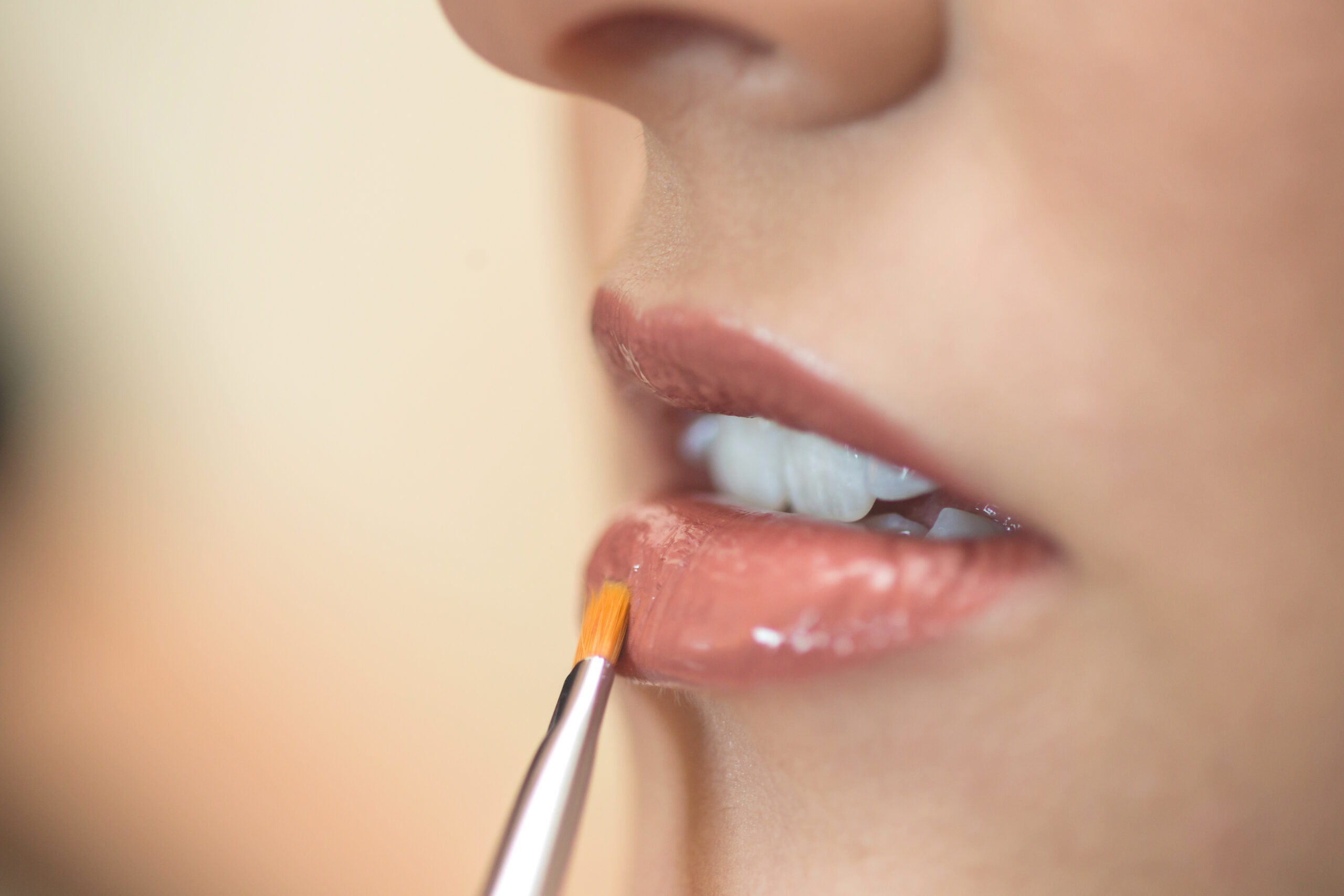 Close-up of an artist's brush applying lip gloss to the bride's lips by Kristy's Artistry Design Team in Orlando.