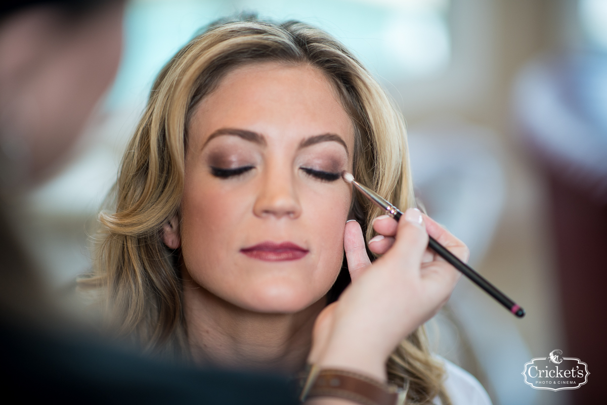 Top makeup artist from Kristy's Artistry Design Team applying finishing touches to a beautiful bride on her wedding day in Orlando.