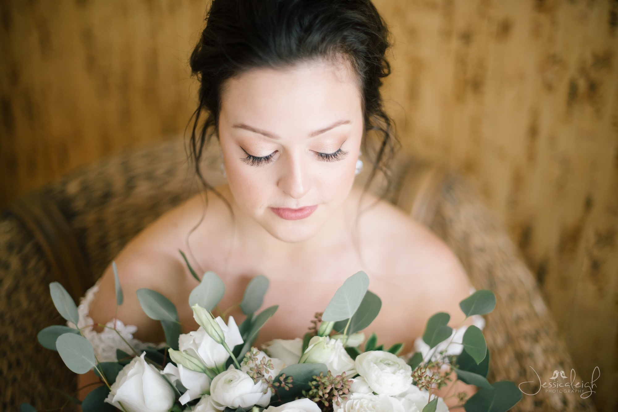 Bride holding a bouquet of flowers, showcasing a close-up of her makeup done by Kristy's Artistry Design Team.