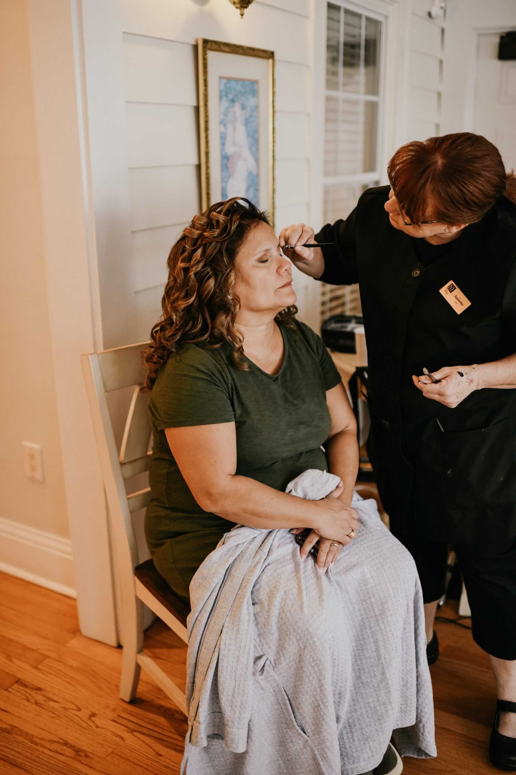 Artist from Kristy's Artistry Design Team applying makeup to a bride with a curly down do hairstyle.