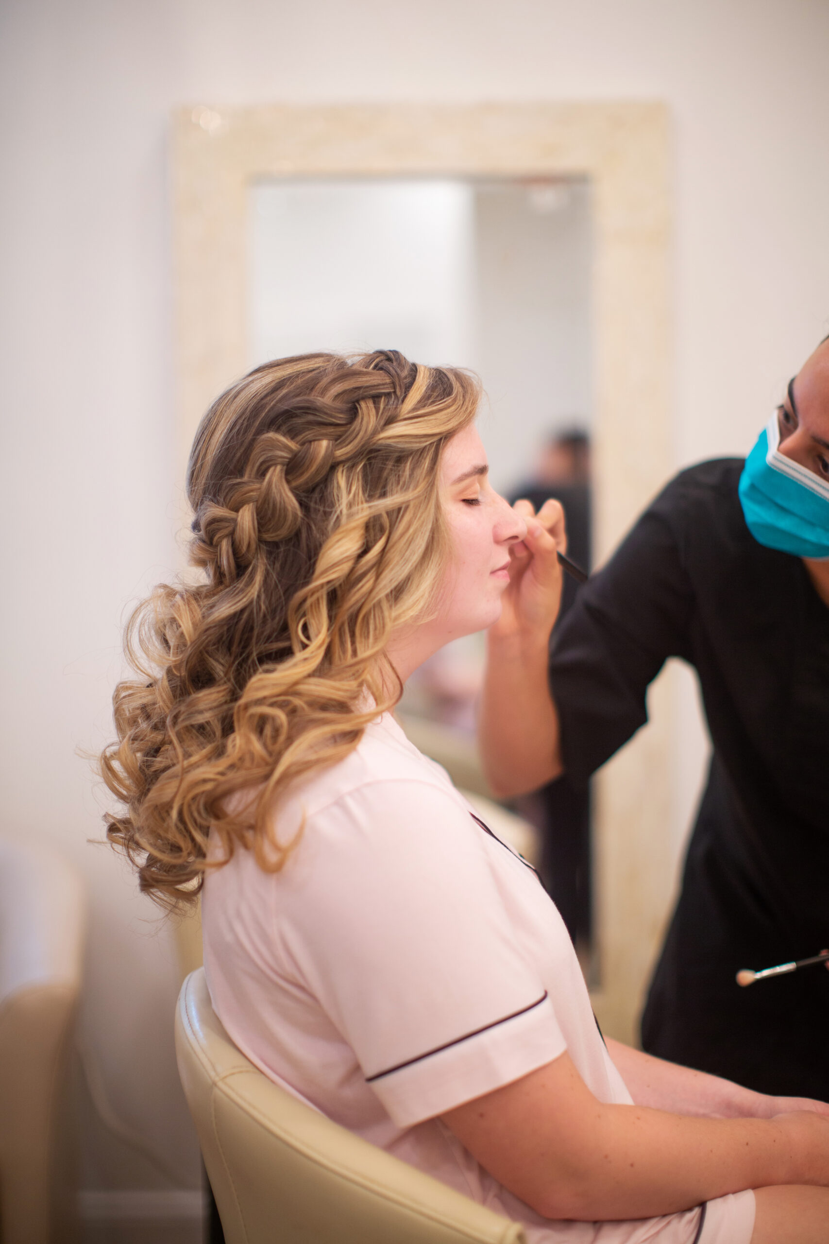 Artist from Kristy's Artistry Design Team applying makeup to a bride with a half up half down hairstyle.