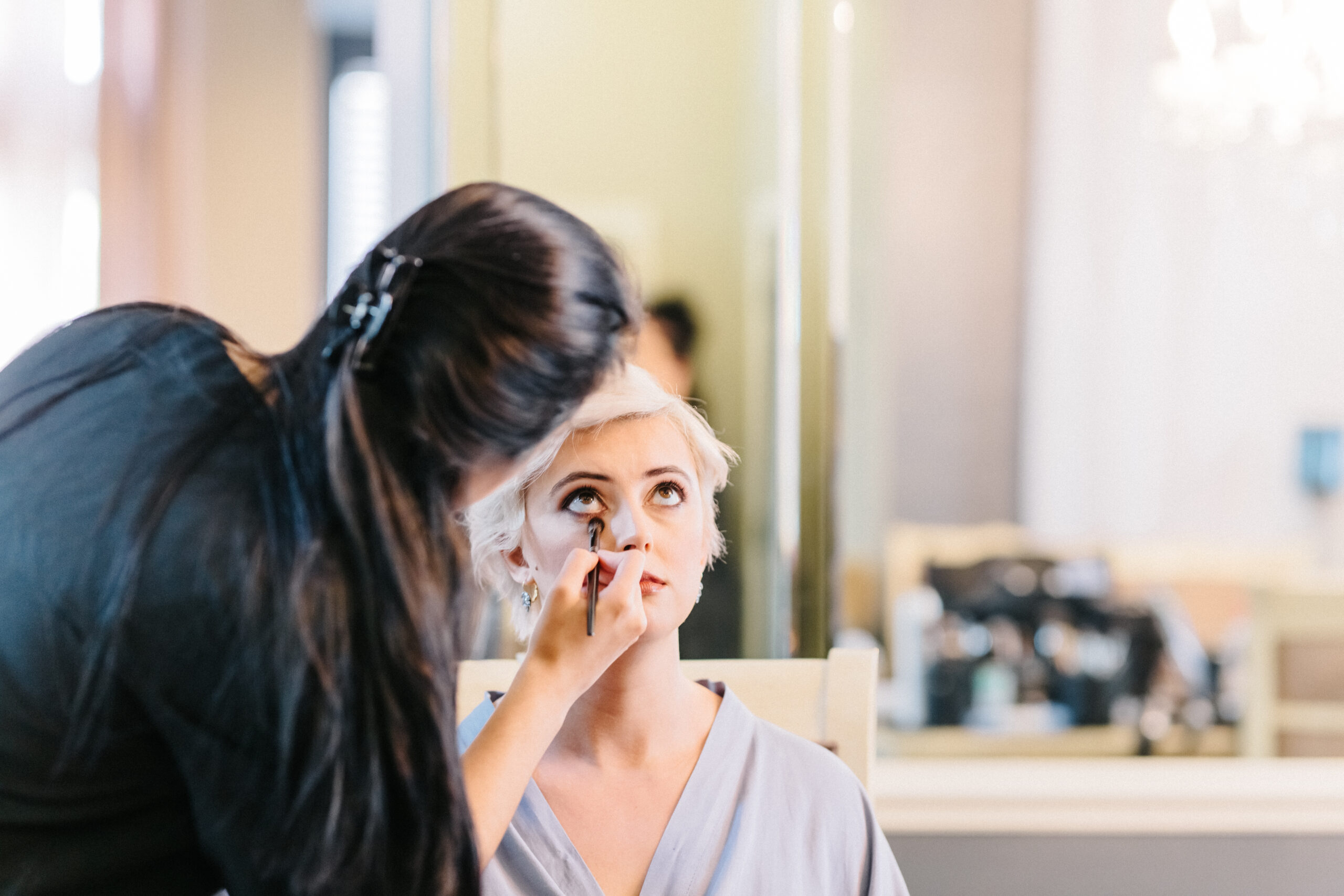 Artist from Kristy’s Artistry Design Team applying eyeshadow under the bride's eye.