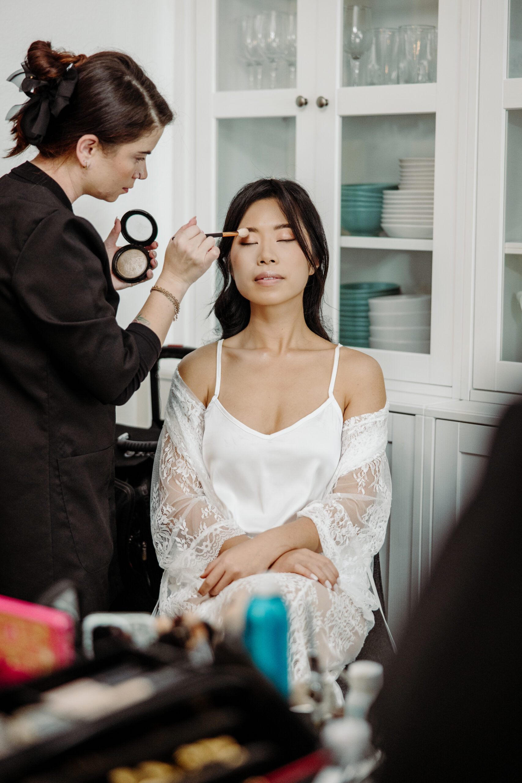 An artist from Kristy's Artistry Design Team, carefully applying color to the bride's eyelids on location.