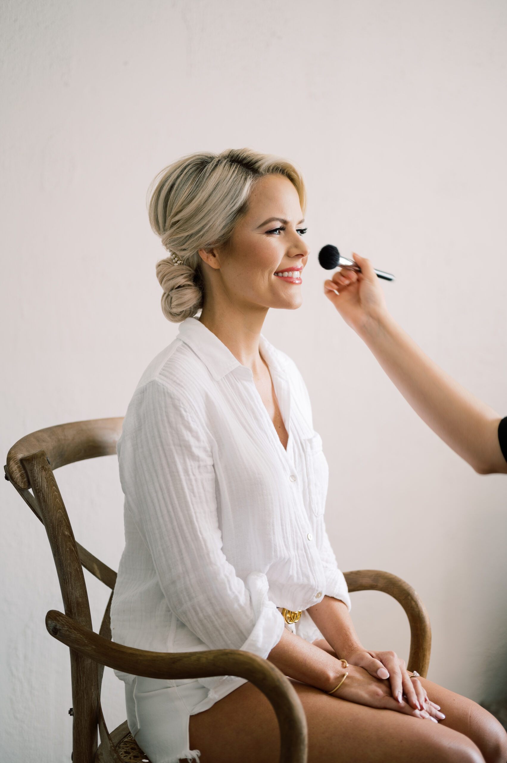 Bride smiling while receiving final touches from Kristy's Artistry Design Team.