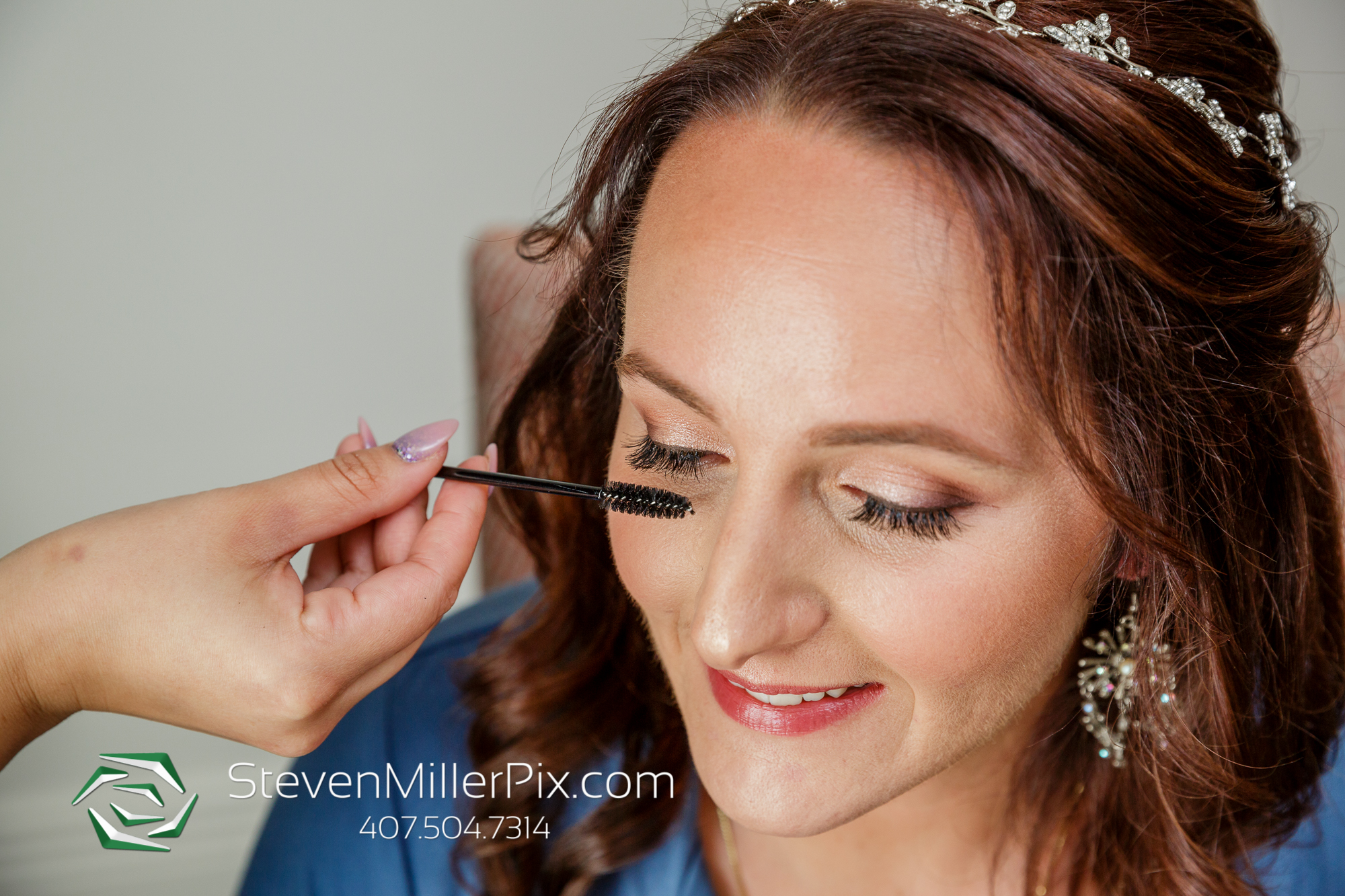 Professional makeup artist from Kristy’s Artistry Design Team applying eyelash filler on a bride wearing a tiara.