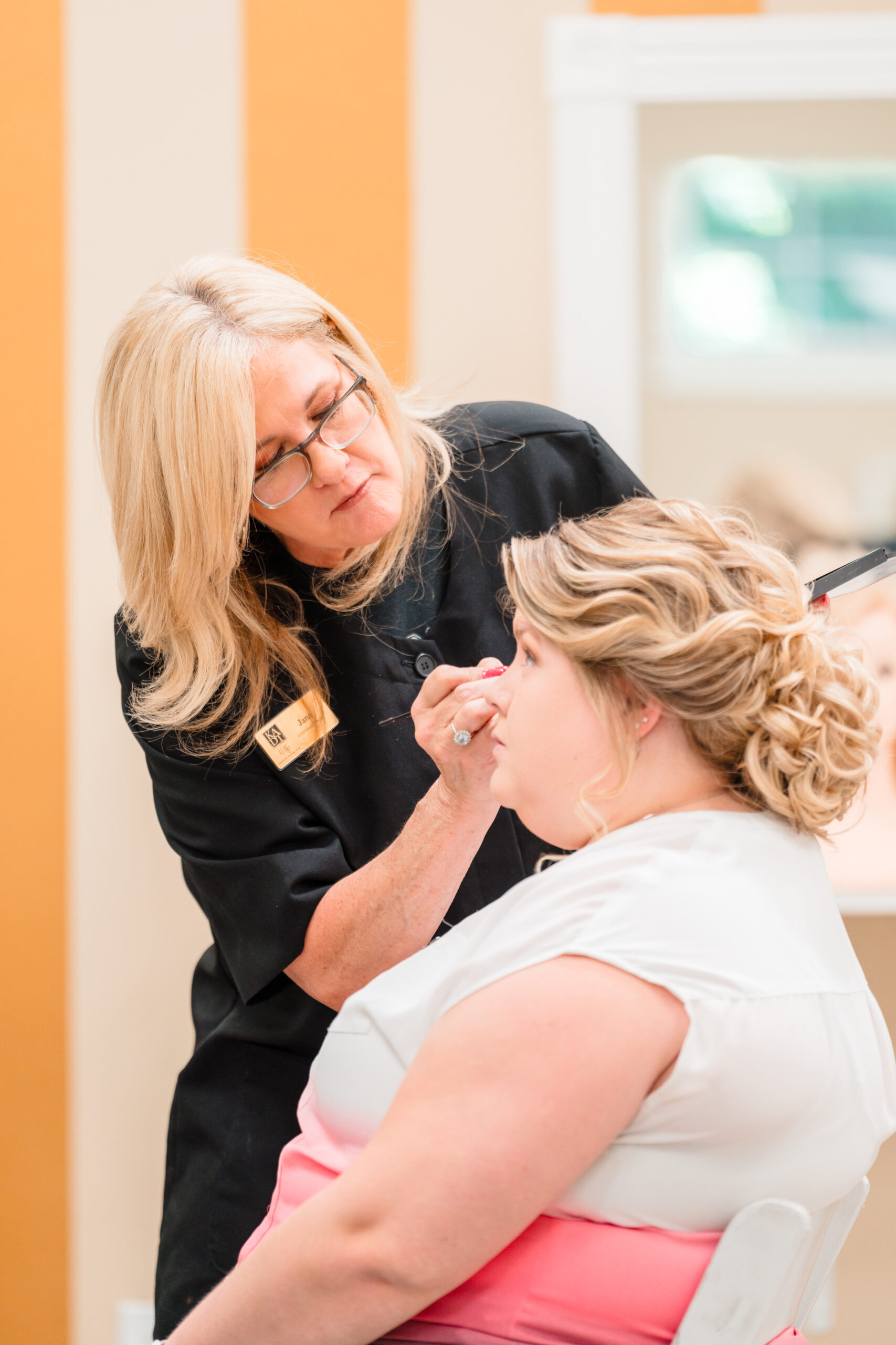 Experienced makeup artist from Kristy's Artistry Design Team working with the bride to achieve her perfect bridal look.