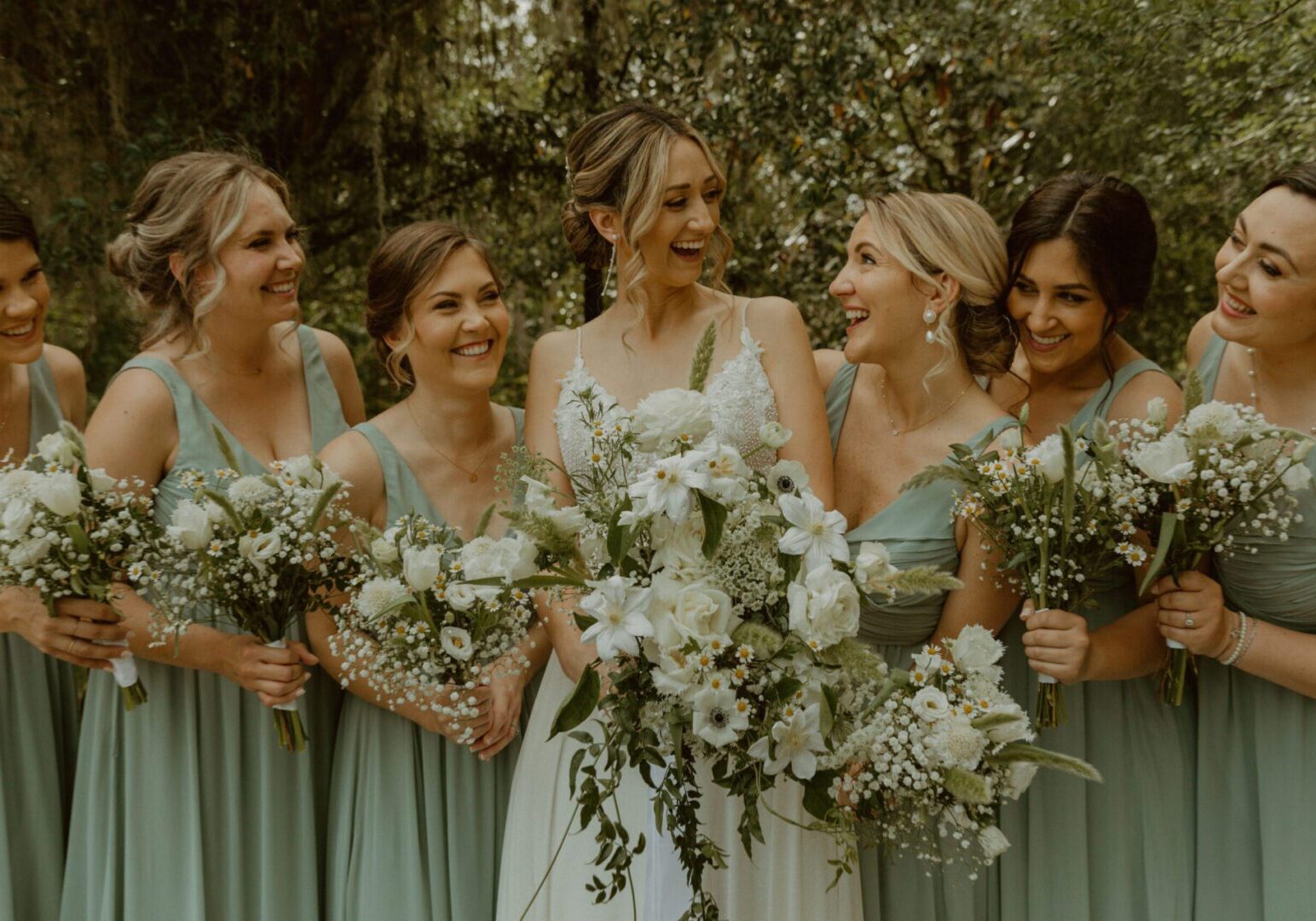 Bridesmaids laughing with bouquets in garden.