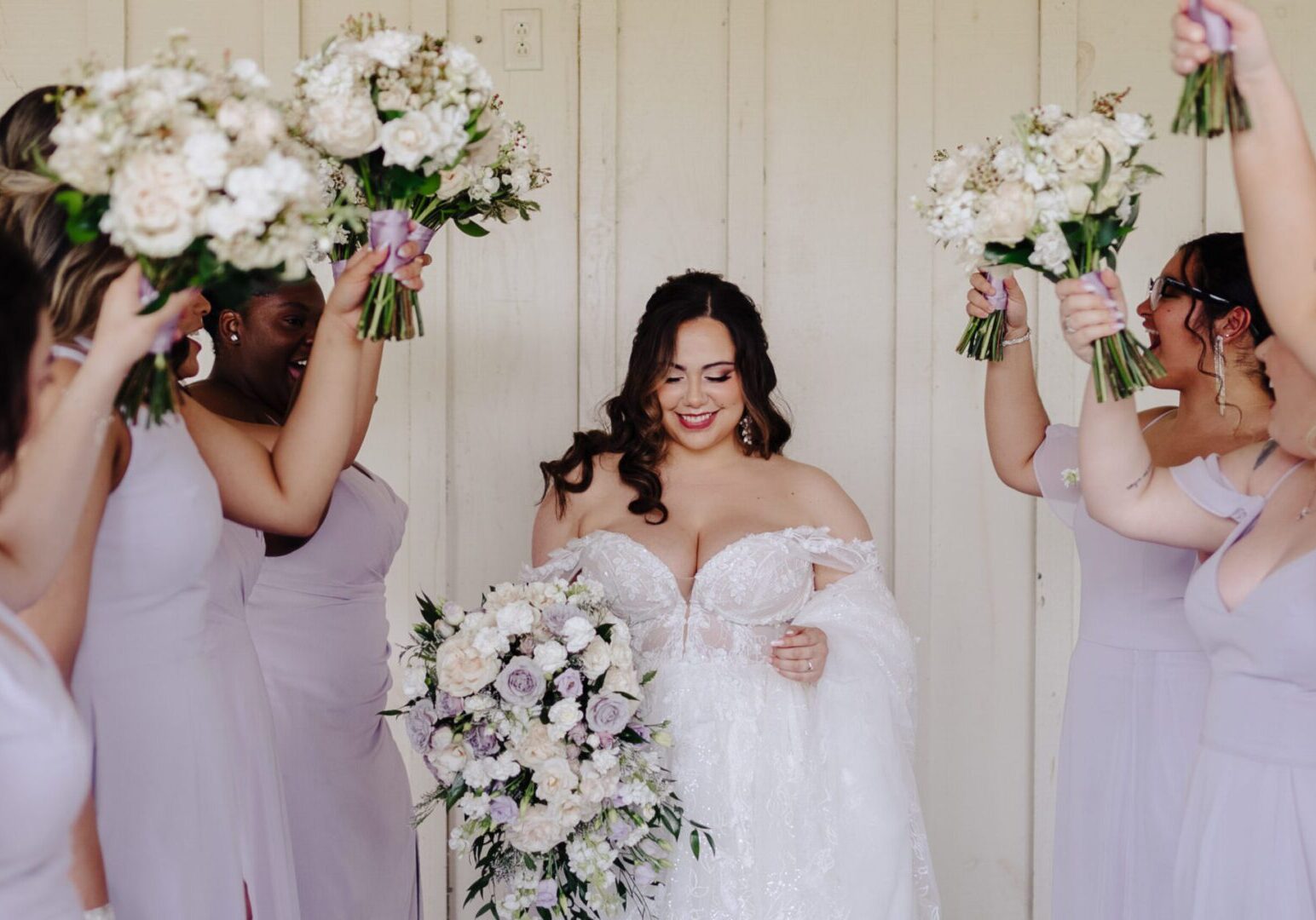 Bride surrounded by bridesmaids holding bouquets.