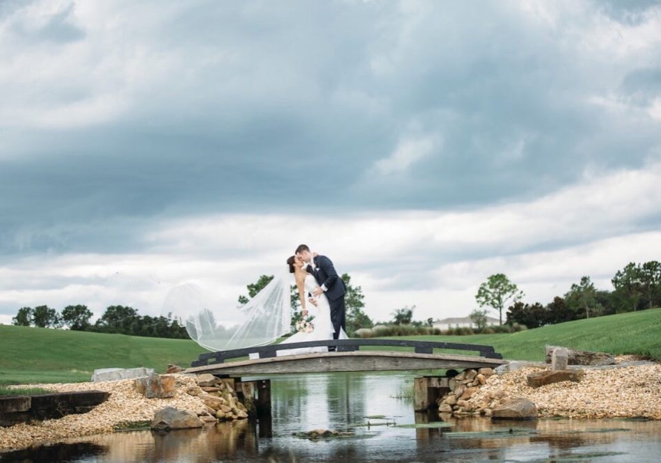 Bride and groom kissing on wooden bridge.