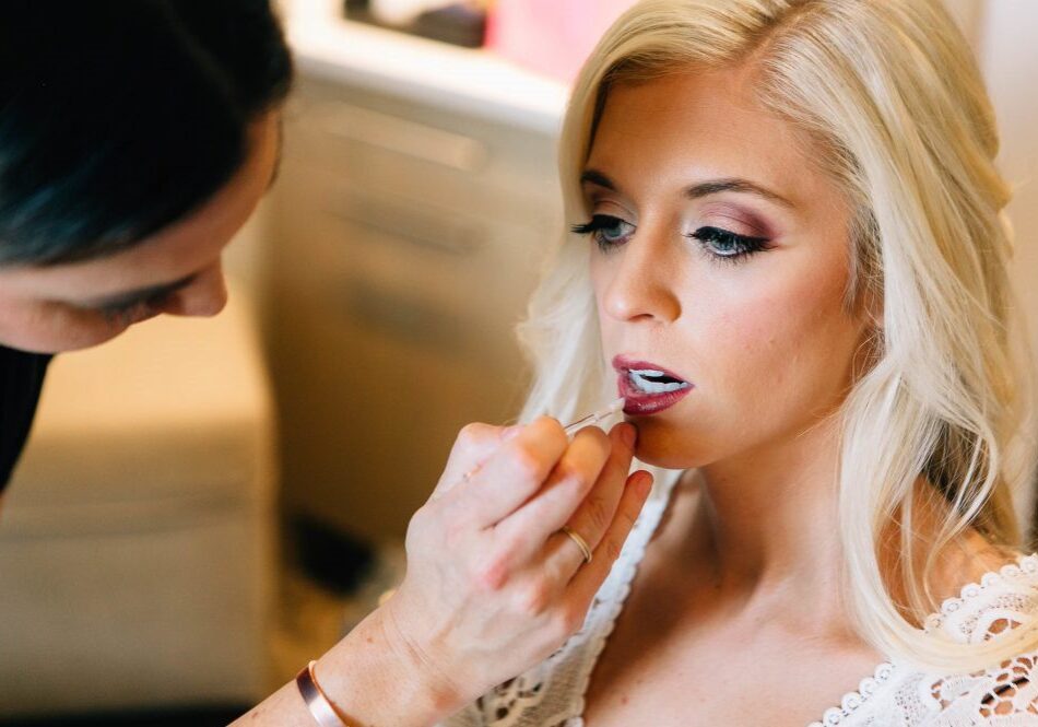Makeup artist applying lipstick to woman.